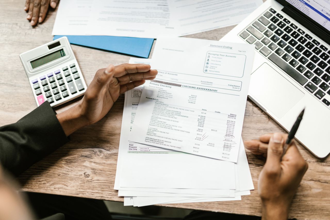Sprawdzanie dokumentów finansowych i wyciągu z kalkulatorem na biurku